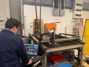 Man using laptop to operate metal fabrication machine