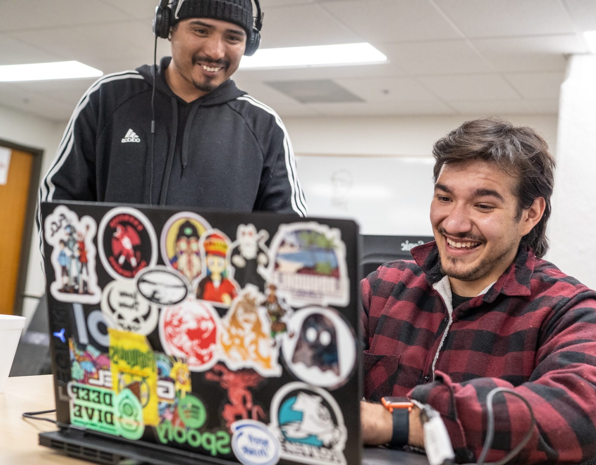 Two students working on a project together on a laptop.